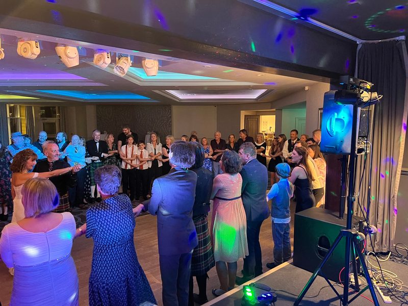 Guests in a ceilidh circle under disco lighting