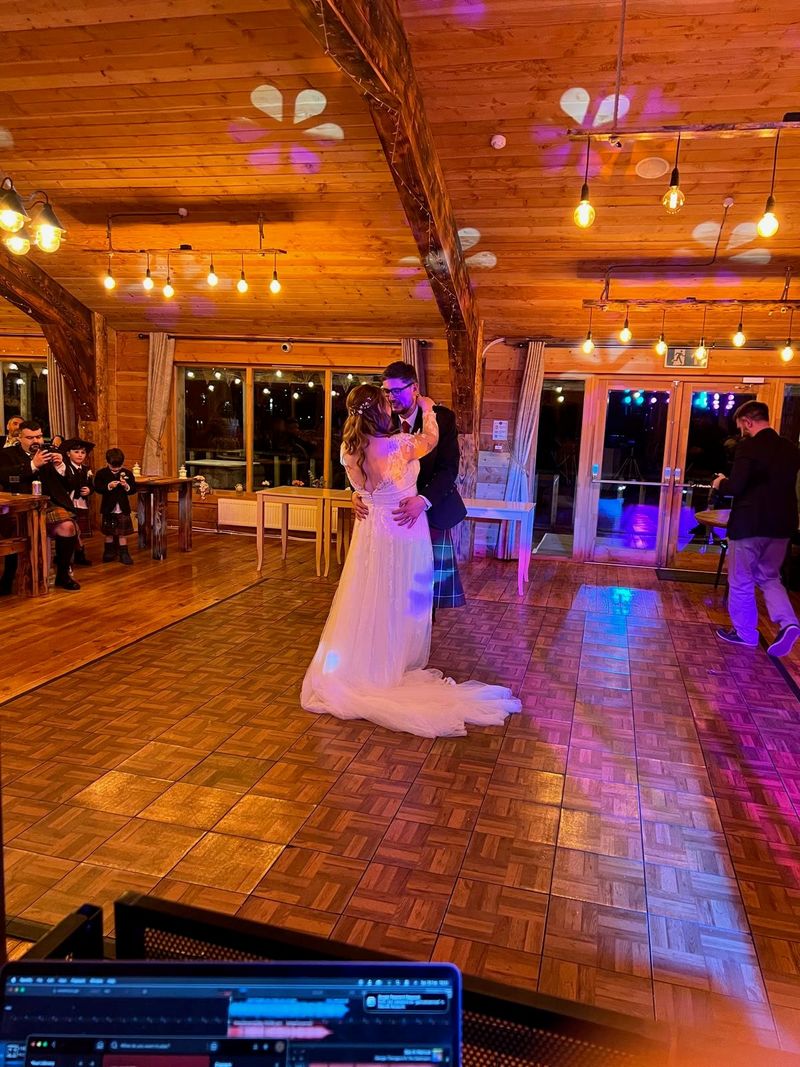 A bride takes the floor under festoon lights in a wedding barn